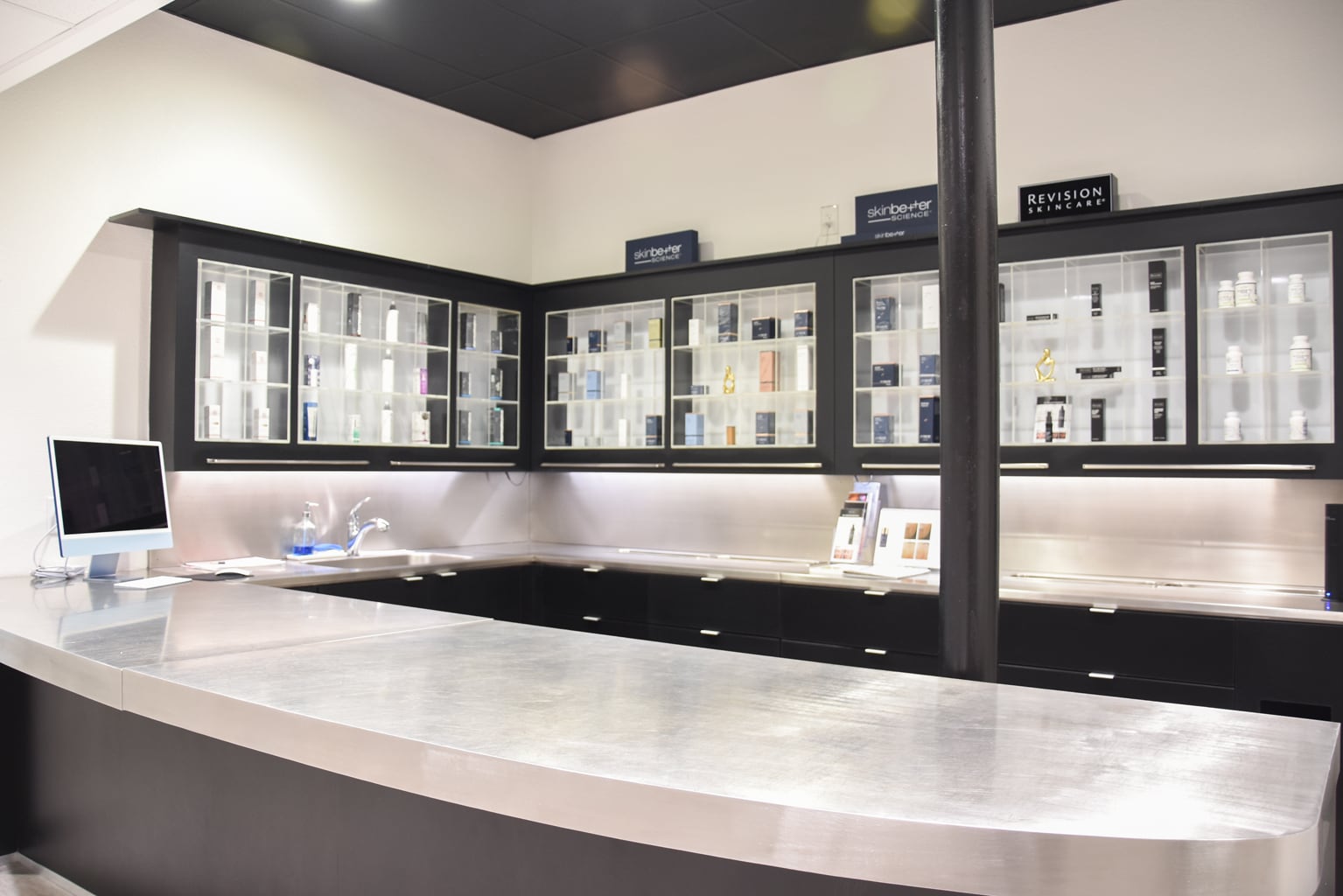 Dark skincare cabinets and curved white countertop in a Harmony Med Spa room