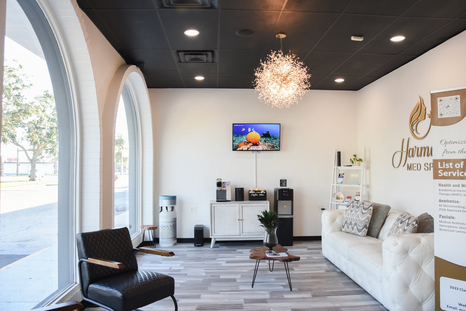 Sunlit Harmony Med Spa waiting room with arched windows, chairs, a sofa, and a chandelier