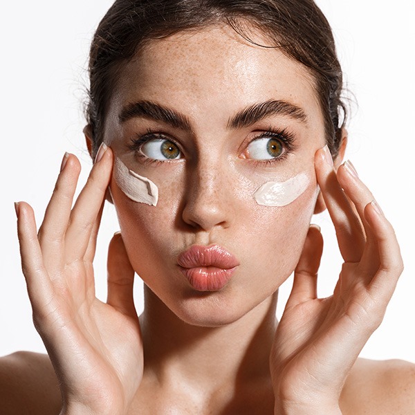 Woman applying skincare cream to her cheeks